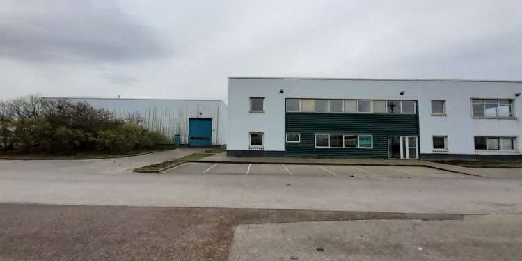 Photographie d'un bâtiment tertiaire doté d'un parking et d'un hangar